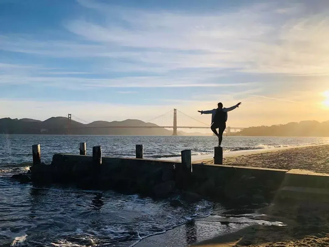 Una donna si trova su un molo nel quartiere Marina di San Francisco, guardando il 金门大桥.