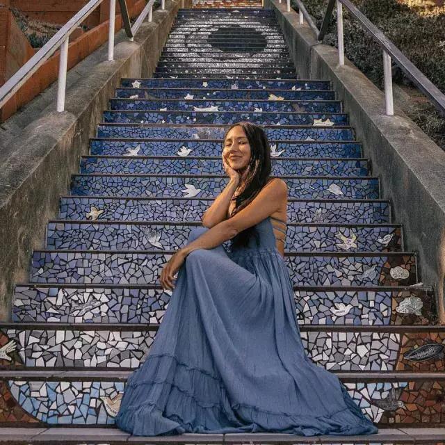 Una mujer posa sentada en las escaleras de azulejos de la Avenida 16 en el barrio Sunset de San Francisco.